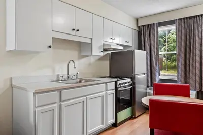 a kitchen with white cabinets and a sink and a refrigerator at Days Inn by Wyndham Lancaster PA Dutch Country in Ronks