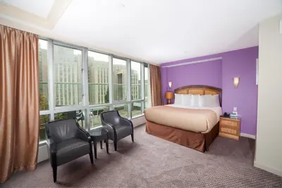 a hotel room with a bed and chairs and windows at Hotel Mulberry in New York