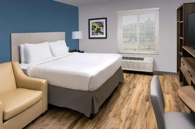 a bedroom with a large bed and a chair at Woodspring Suites Cherry Hill in Cherry Hill
