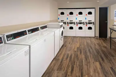 a laundry room with white washing machines and wooden floors at Woodspring Suites Cherry Hill in Cherry Hill