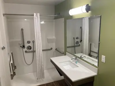 a bathroom with a shower and a sink and a mirror at Woodspring Suites Cherry Hill in Cherry Hill