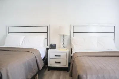 a bedroom with two beds and a night stand with a lamp at The Lancaster Motel By OYO Ronks near Paradise in Ronks