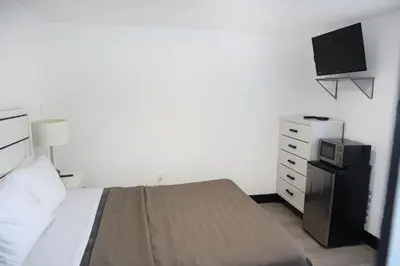 a bedroom with a bed and a dresser with a television at The Lancaster Motel By OYO Ronks near Paradise in Ronks