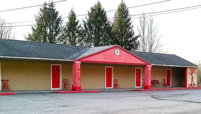 a building with red doors and chairs in a parking lot at Buena Vista Inn Motel in Delhi