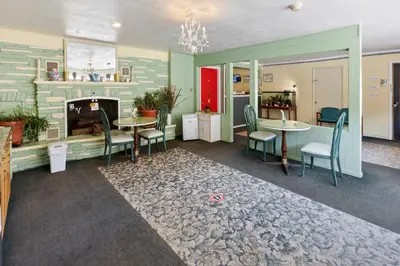 a living room with a fireplace and tables and chairs at Buena Vista Inn Motel in Delhi