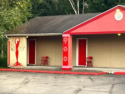 a small building with red doors and red chairs at Buena Vista Inn Motel in Delhi
