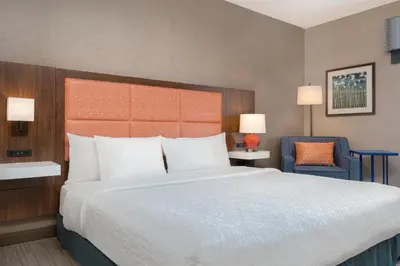 a bedroom with a large bed and a blue chair at Hampton Inn & Suites Wilkes-Barre in Wilkes-Barre