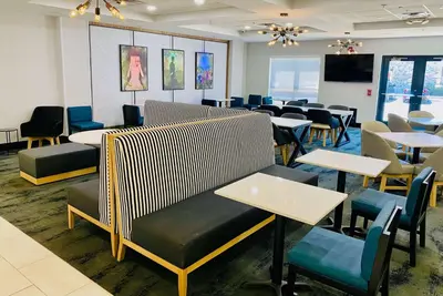 a waiting room with tables and chairs and a screen at La Quinta by Wyndham Mt. Laurel - Philadelphia in Mount Laurel
