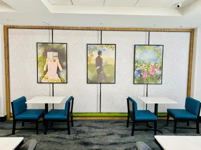 a room with tables and chairs and paintings on a wall at La Quinta by Wyndham Mt. Laurel - Philadelphia in Mount Laurel
