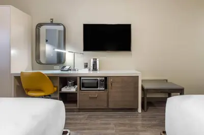 a hotel room with a desk with a microwave and a tv at Cambria Hotel Philadelphia Downtown - Center City in Philadelphia