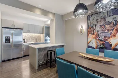 a kitchen and dining room with a wooden table and blue chairs at Cambria Hotel Philadelphia Downtown - Center City in Philadelphia