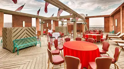 a restaurant with red tables and chairs on a deck at Robert Treat Hotel in Newark