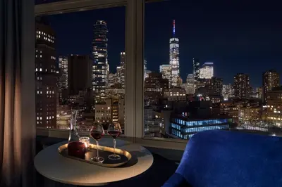 a room with a window with a table and two glasses of wine at ModernHaus SoHo in New York