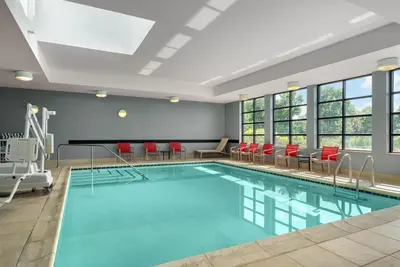 a swimming pool with red chairs and a large room with windows at Homewood Suites by Hilton Newtown - Langhorne, PA in Newtown