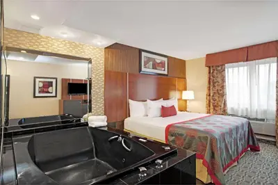 a hotel room with a bed and a bath tub at Ramada by Wyndham Staten Island in Staten Island