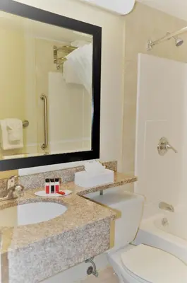 a bathroom with a sink and a toilet and a mirror at Ramada by Wyndham Staten Island in Staten Island