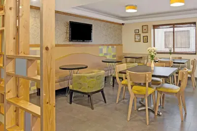 a dining room with tables and chairs and a tv at Ramada by Wyndham Staten Island in Staten Island