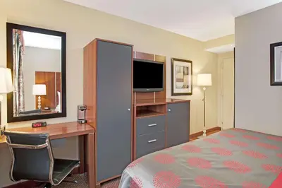 a hotel room with a bed and a desk and a television at Ramada by Wyndham Staten Island in Staten Island