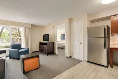 a living room with a refrigerator and a bedroom at Homewood Suites by Hilton Wilmington-Brandywine Valley in Talleyville