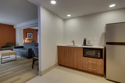 a kitchen with a refrigerator and a living room at Holiday Inn Express Voorhees/ Mt. Laurel by IHG in Voorhees