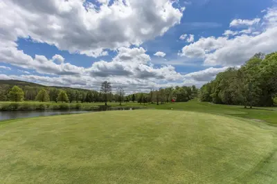 a golf course with a green field and a river at The Appalachian at Mountain Creek in Vernon