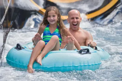 a man and a little girl sitting on an inner tube in the water at The Appalachian at Mountain Creek in Vernon