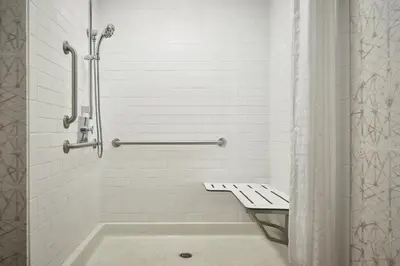 a bathroom with a shower with a bench and a tub at Courtyard by Marriott Philadelphia Downtown in Philadelphia