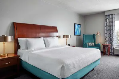 a bedroom with a large bed and a blue chair at Hilton Garden Inn Allentown West in Breinigsville
