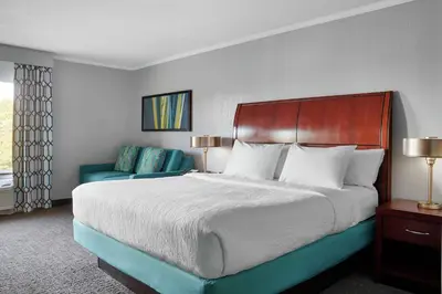 a bedroom with a large bed and a blue chair at Hilton Garden Inn Allentown West in Breinigsville
