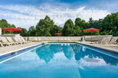 a swimming pool with chairs and umbrellas at Ramada by Wyndham Allentown Bethlehem in Allentown