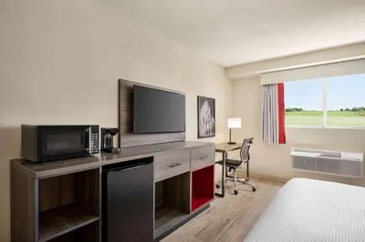 a hotel room with a desk with a microwave and a television at Ramada by Wyndham Allentown Bethlehem in Allentown