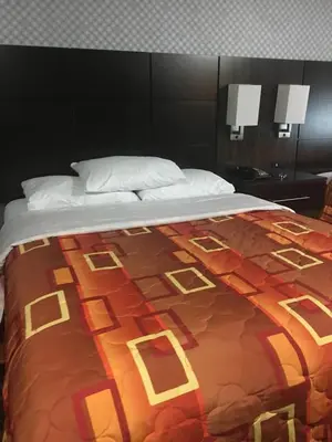 a large bed with a colorful blanket on it at Red Carpet Inn Elmwood in Elmwood Park