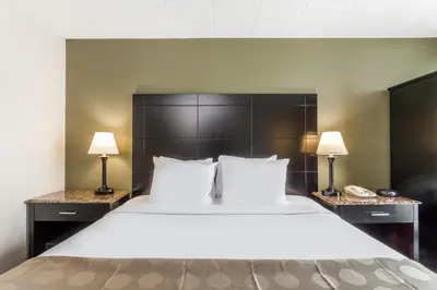 a large bed in a hotel room with two lamps at Ramada by Wyndham Newburgh/West Point in Newburgh