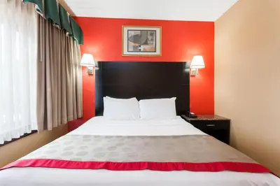 a bed in a hotel room with red walls at Ramada by Wyndham Newburgh/West Point in Newburgh