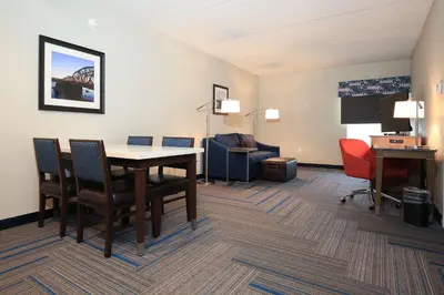a hotel room with a desk and a table and chairs at Hampton Inn Bordentown in Bordentown