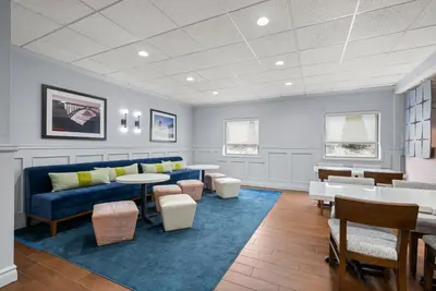 a waiting room with a blue couch and tables and chairs at Hampton Inn Bordentown in Bordentown