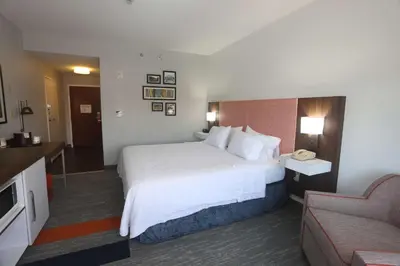 a hotel room with a large bed and a couch at Hampton Inn Owego in Owego