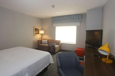 a hotel room with a bed and a tv and a chair at Hampton Inn Owego in Owego