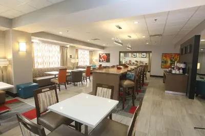 a restaurant with a bar and tables and chairs at Hampton Inn Owego in Owego