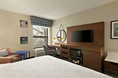 a hotel room with a bed and a desk with a television at Hampton Inn Binghamton/Johnson City in Binghamton
