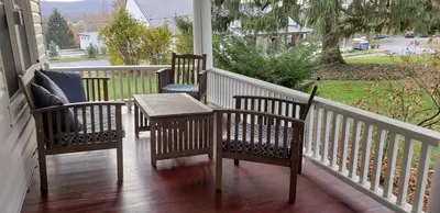 a porch with three chairs and a table on a porch at Allenberry Resort in Carlisle