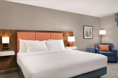 a bedroom with a large bed and a blue chair at Hampton Inn Bloomsburg in Bloomsburg