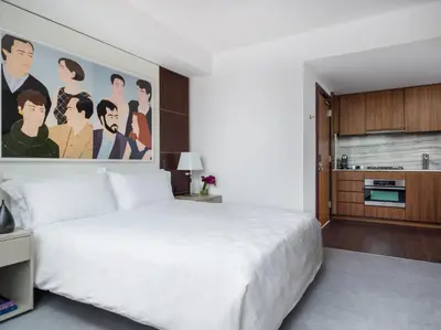 a bedroom with a large white bed and a kitchen at The Langham, New York, Fifth Avenue in New York