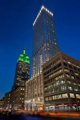 two tall buildings in a city at night at The Langham, New York, Fifth Avenue in New York
