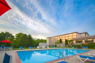 a pool at a hotel with chairs and a building at Chester Hotel and Conference Center in Exton
