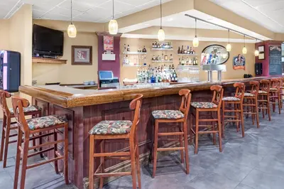 a bar with a row of wooden bar stools at Chester Hotel and Conference Center in Exton