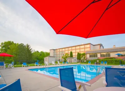 a pool with a red umbrella and a hotel at Chester Hotel and Conference Center in Exton