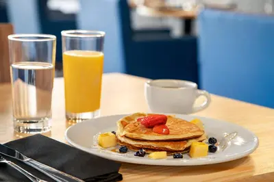 a plate of pancakes with fruit and a glass of orange juice at Holiday Inn Philadelphia Arpt-Stadium Area by IHG in Philadelphia