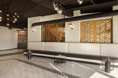 a lobby with a wall with wooden screens and tables at Holiday Inn Philadelphia Arpt-Stadium Area by IHG in Philadelphia