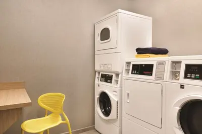 a laundry room with a washer and a yellow chair at Tru By Hilton York Pa in York